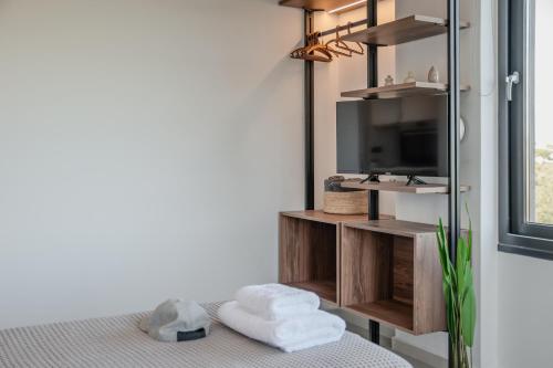 Una habitación con televisión y una cama con toallas. en Allargo Project, en Gerani