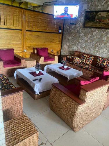 a restaurant with tables and wicker chairs and a television at Ma'a Lapseu hôtel in Yaoundé