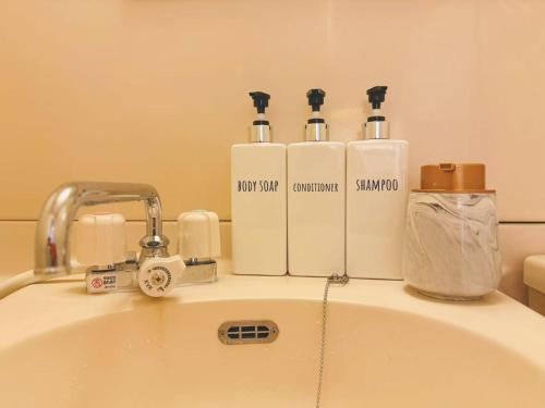 a bathroom sink with three bottles ofodorizers on it at Shinjuku Downtown新宿 in Tokyo