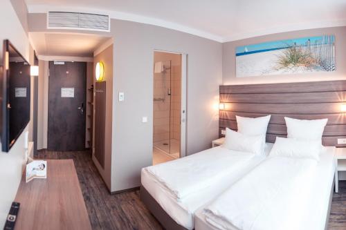 Schlafzimmer mit einem großen weißen Bett mit einem Kopfteil aus Holz in der Unterkunft Tulip Inn München Messe in München