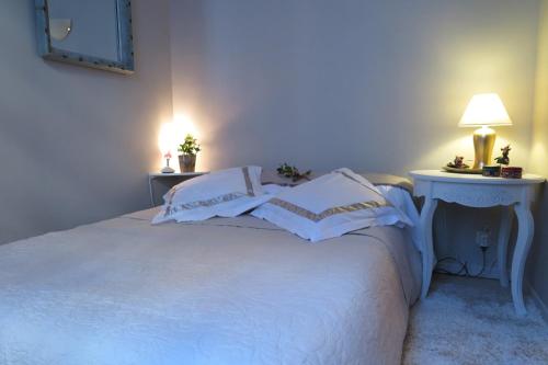 a bedroom with a white bed with two tables and a lamp at L'Oustal du Sentier in Mur-de-Barrez