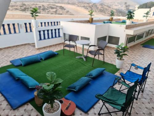 a patio with blue pillows and chairs on a lawn at blue door imsouane in Imsouane