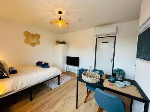 a room with a bed and a table and a tv at L'Ecume - Le Rheu in Le Rheu