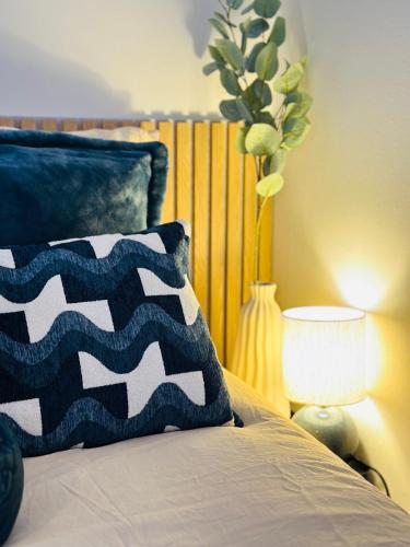 a bed with a blue and white pillow and a lamp at L'Ecume - Le Rheu in Le Rheu
