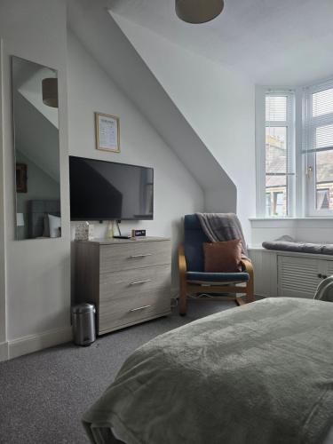 a bedroom with a flat screen tv and a chair at Castleblair Snug - Entire Flat in Dunfermline in Dunfermline
