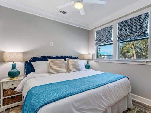 a bedroom with a blue and white bed with two windows at Beachside Villa Unit 3 in Tybee Island