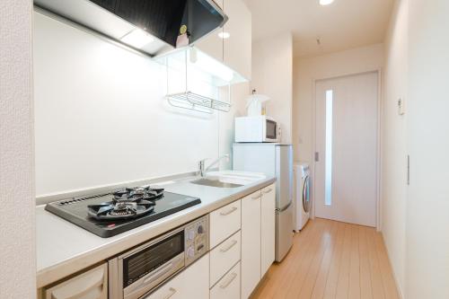 a kitchen with a stove and a sink and a refrigerator at ハイツNagomi-京都駅まで25分 in Otsu