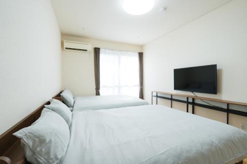 a bedroom with two beds and a flat screen tv at ハイツNagomi-京都駅まで25分 in Otsu