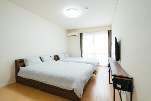 a bedroom with two beds and a television in it at Heights Nagomi in Otsu