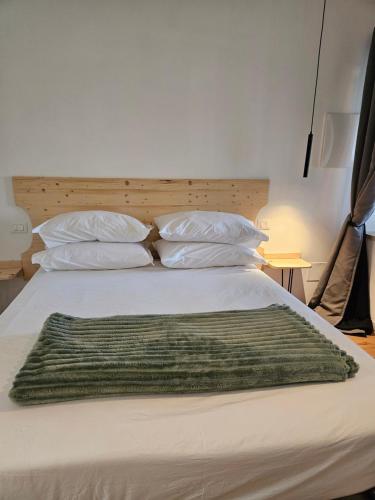 a bed with a green blanket on top of it at Dolcevita guest house in Torreano