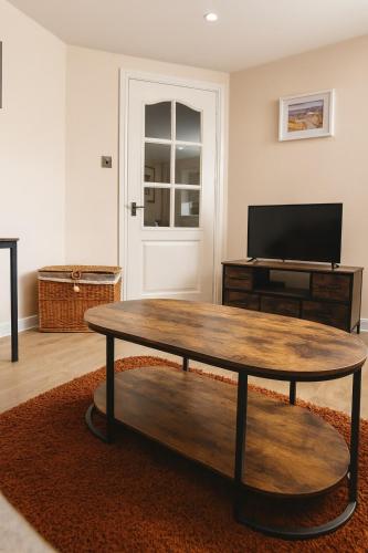 a living room with a table and a tv at Erskine Apartment-Small and Cosy 1 Bedroom Apartment in Angus