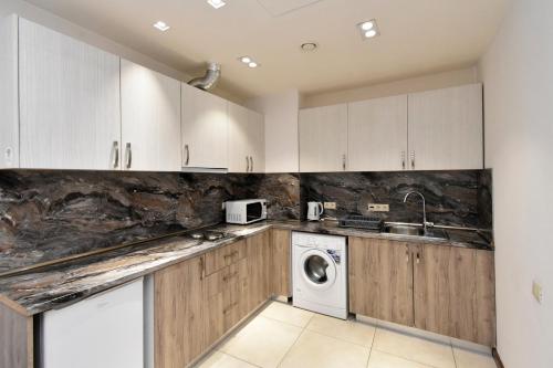 a kitchen with white cabinets and a washer and dryer at Ararat View Apartments in Yerevan