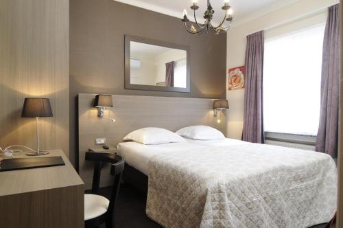 a hotel room with a bed and a mirror at Hotel Albert I in Bruges