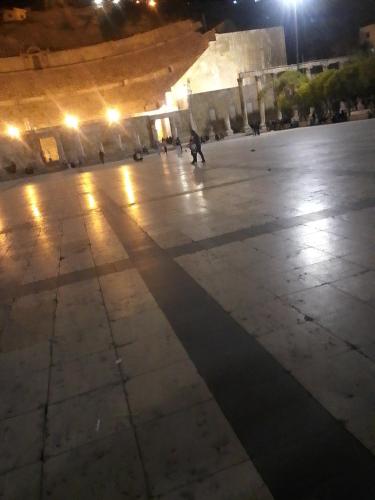 a person walking in an empty plaza at night at وسط البلد عمان in Amman