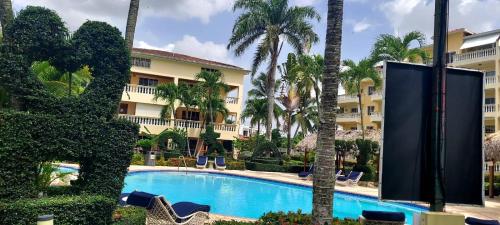 a swimming pool in front of a hotel with palm trees at Marvilla - Coastal Condo Poolside & Ocean View in Boca Chica