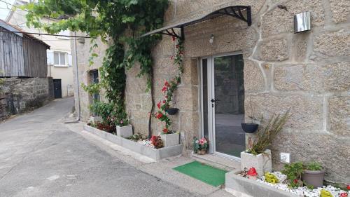 a stone building with flowers in front of a door at Casa Maria da Eira in Arcos de Valdevez