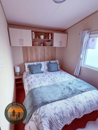 a bedroom with a bed with a blue comforter and a window at 3 Bedroom Caravan with stunning panoramic sea view in New Quay