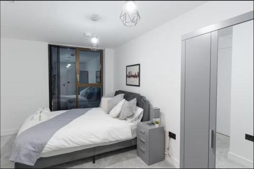 a white bedroom with a bed and a mirror at Manchester Guesthouse in Manchester