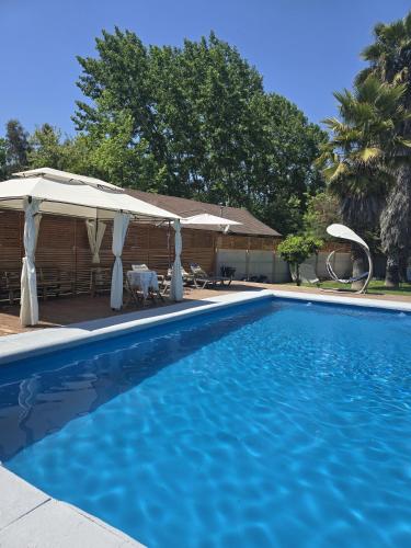 a swimming pool with an umbrella and a house at Casa Uri in San Fernando