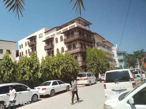 two people walking down a street in front of a building at Darajani Apartment in Zanzibar City