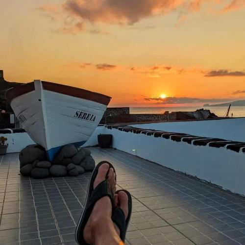 a person with their feet up on a roof watching the sunset at Casa do Guardião in Madalena