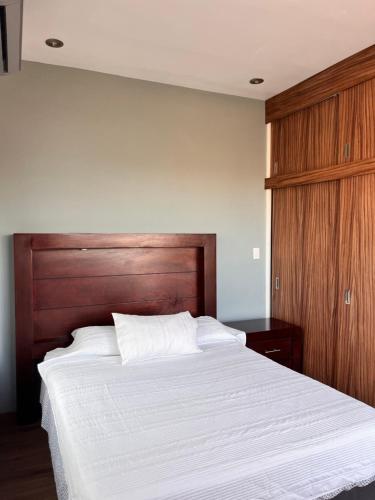 a bedroom with a large bed with a wooden headboard at Puerta Sevilla in Saltillo