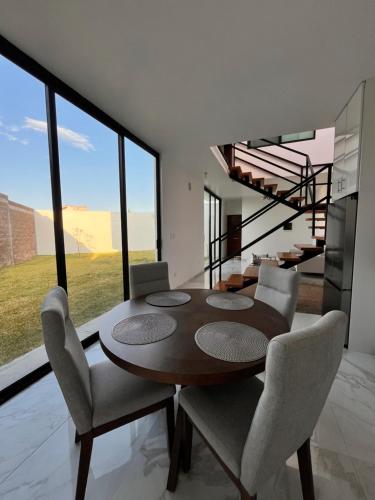 a dining room with a table and chairs and a staircase at Puerta Sevilla in Saltillo