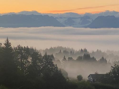 a foggy valley with a house and mountains in the background at Apartment, walkout basement, Central Homer, Views! in Homer