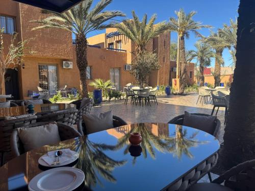 a patio with tables and chairs and palm trees at RS Hôtel Karam Resort in Ouarzazate