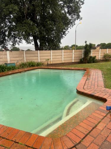 a swimming pool with blue water in a yard at Ruros Guest House in Kempton Park
