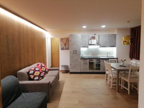 a living room and kitchen with a couch and a table at Chalet 5 Laghi / LuxApt / Town Centre in Madonna di Campiglio