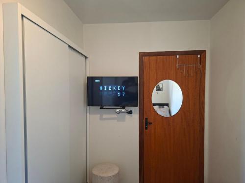 a door with a television next to a door with a window at AP compartilhado Quarto aconchegante em Camboriú 10 min de BC in Camboriú