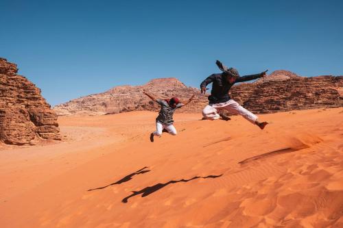 due persone che saltano nella sabbia nel deserto di Sunrise Magic Camp a Wadi Rum