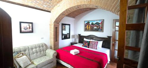 a bedroom with a red bed and a couch at Casa Santiago Son 2 in Antigua Guatemala