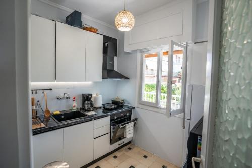 eine Küche mit weißen Schränken und einer Spüle und einem Fenster in der Unterkunft Beachfront Lagonisi Apt 1 Minute From Grand Resort in Kalívia Thorikoú