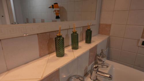 three green bottles sitting on a shelf in a bathroom at Spazioso appartamento vicino a tutto in Tortona
