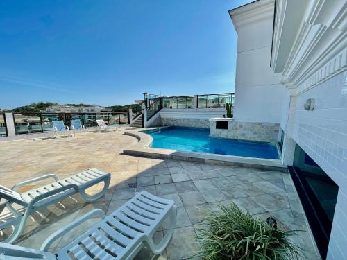 Un patio con sillas y una piscina. en Loft Prainha - VISTA MAR, en Arraial do Cabo