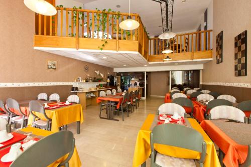 a restaurant with yellow and orange tables and chairs at Cit'Hotel Du Circuit in Magny-Cours