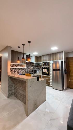 a large kitchen with a counter and a refrigerator at Conforto & Sofisticação in Macapá