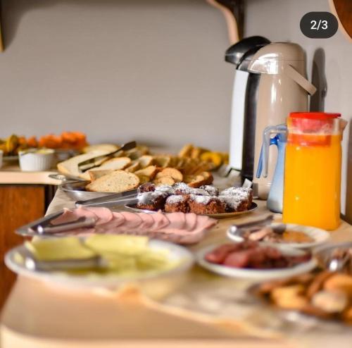 a table topped with plates of food and orange juice at Novo Hotel in Caçapava do Sul
