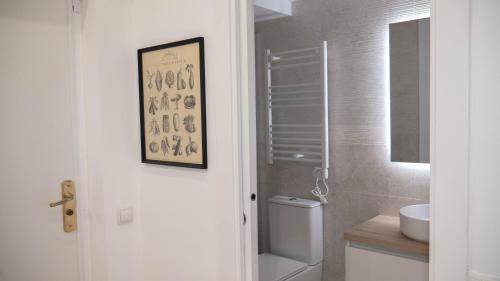 a white bathroom with a toilet and a sink at Apartamento Preciados in Madrid