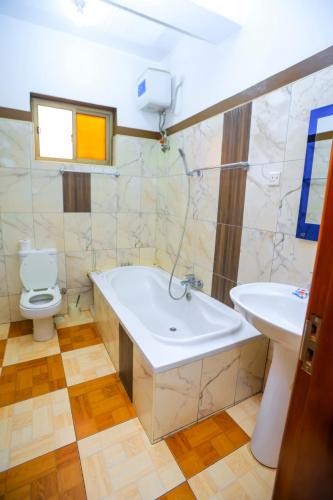 a bathroom with a tub and a toilet and a sink at Hotel Acacia View in Kampala