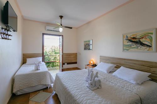 Un dormitorio con dos camas con sábanas blancas. en Hotel Pirá Miúna, en Bonito