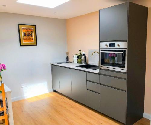 a kitchen with a stove and a microwave at Modern Self Contained Garden Annexe Sleeps up to 4 in Forest Hill