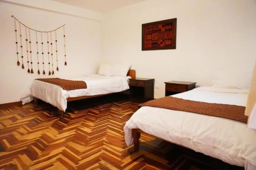 Habitación con 2 camas y suelo de madera. en Shanti Hotel Pisac, en Písac