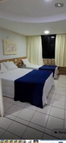 Una habitación de hotel con dos camas con sábanas azules. en Atlântico Flat, en Natal
