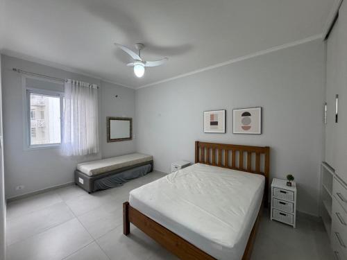 a white bedroom with a bed and a window at Ap Pitangueiras - 3 suítes - Pé na Areia - Ao lado do Shopping in Guarujá