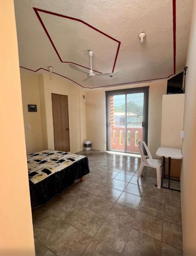 une chambre avec un lit, une table et une fenêtre dans l'établissement Hostal Color Inn, à Santo Domingo Tehuantepec