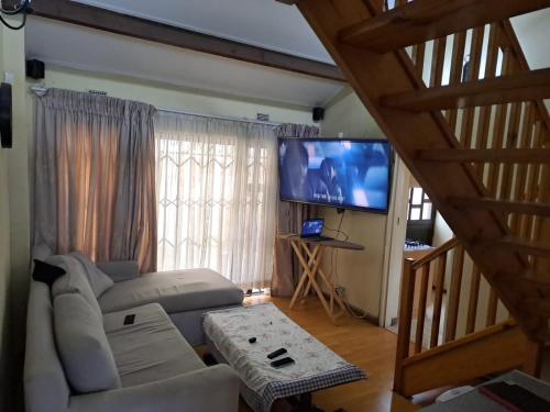 a living room with a couch and a flat screen tv at Gugu's Holiday Home in Durban