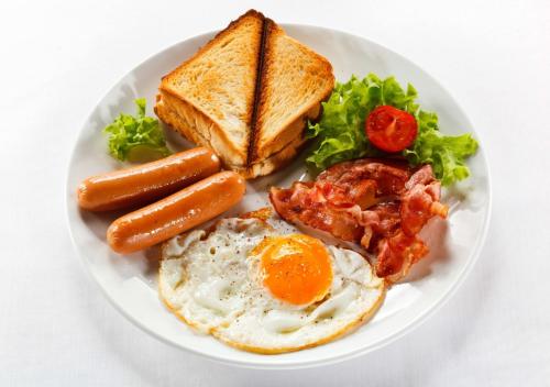 a plate of breakfast food with eggs bacon sausage and toast at Home Hotel Kutaisi in Kutaisi